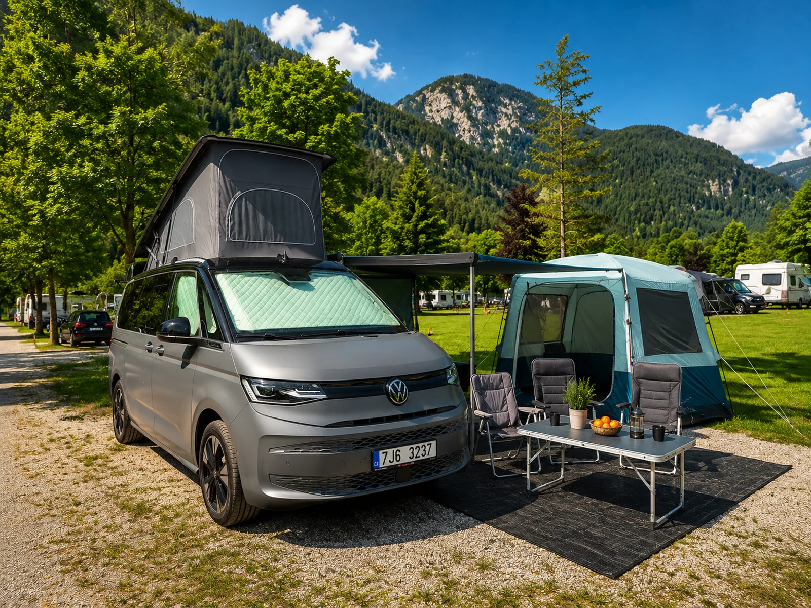 VW California s vysunutou pop-top střechou a markýzou — alpský kemp